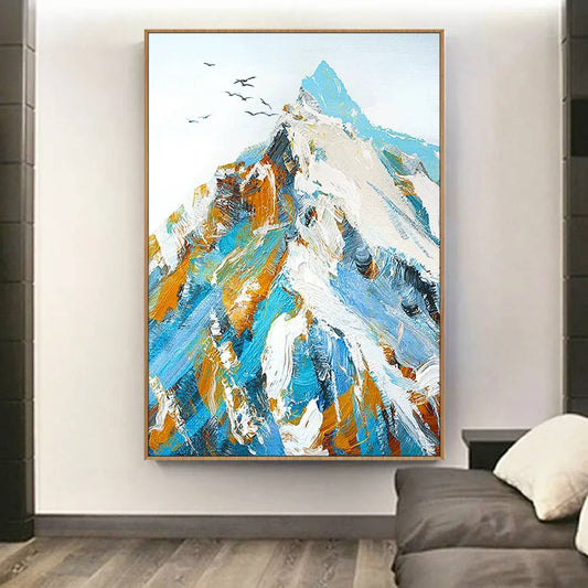 Room mockup. A sharp mountain peak formed from white, turquoise, blue and ochre strokes, with small dark birds against a pale sky.